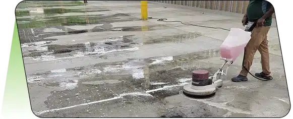 A wet, partially cleaned concrete or paved surface with a yellow bollard in the background.
