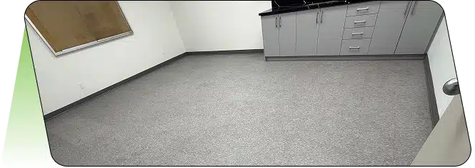 An empty room with light-colored flooring and a dark counter area.