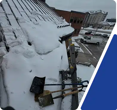 Snow covering the roof of a building overlooking a parking lot.