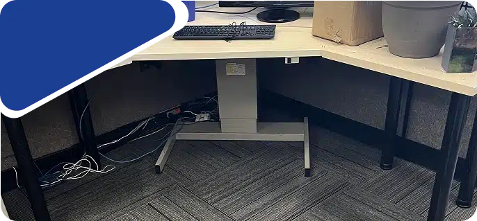 Underneath a office desk showing the leg and carpet floor.