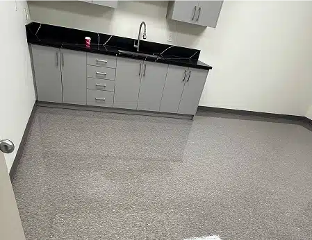 An empty break room or kitchen with light grey cabinets and a black countertop.