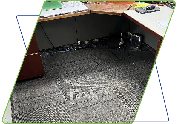 An office desk corner over gray carpet tiles, framed with blue and green graphics.