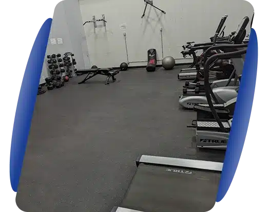 A gym room with exercise equipment and rubber flooring.