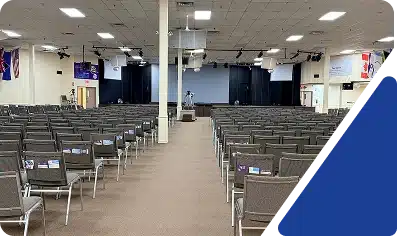 A large auditorium or place of worship with many rows of chairs facing a stage area.
