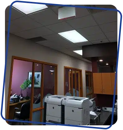 View looking up at an office ceiling with square tiles and fluorescent lights.