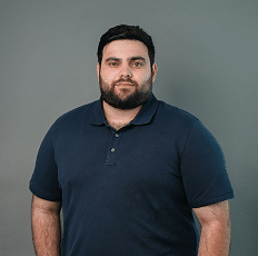 Headshot of a man with a beard wearing a dark blue polo shirt.