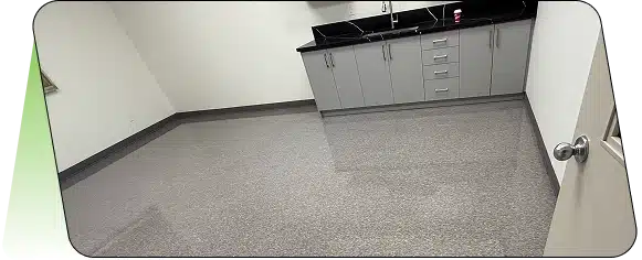 A clean floor in front of white lab cabinets with a dark countertop.