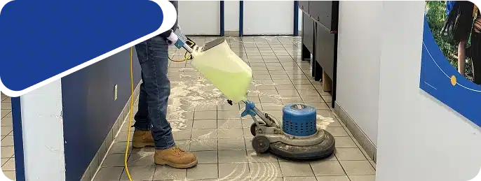 A worker operating a floor buffing machine on tiled flooring.