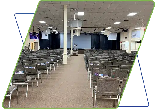 A large auditorium or place of worship with many rows of chairs facing a stage area.