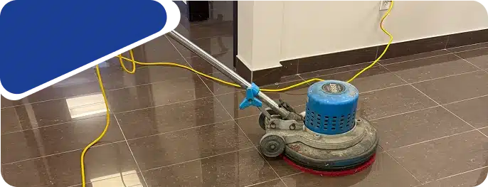 A blue floor buffing machine on a shiny brown tiled floor, framed by a blue graphic.