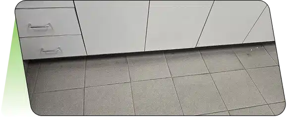 A view of white base cabinets above a light-colored tiled floor.