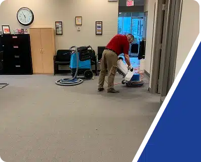 A person vacuuming the carpet in an office reception or waiting area.