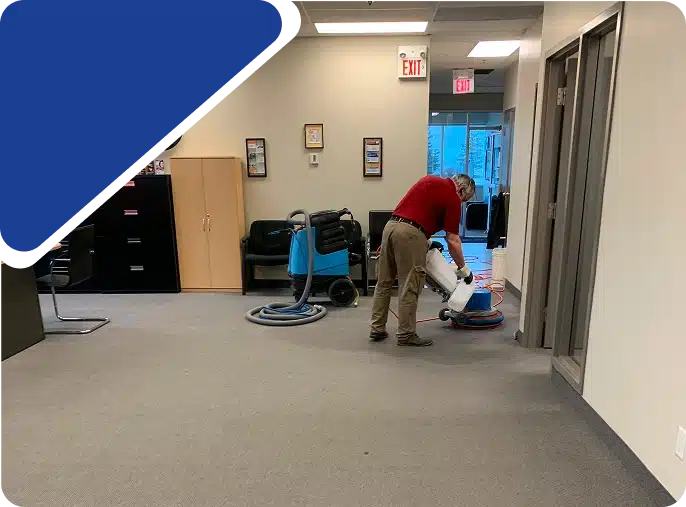 A person vacuuming an office hallway, framed by a blue graphic.