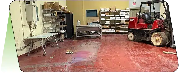 A storage room or workshop with red flooring and metal shelving units.