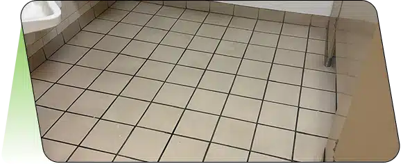 A close-up view of light-colored square floor tiles with dark grout.