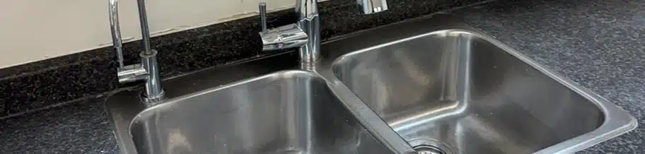 A close-up of a clean stainless steel double kitchen sink.