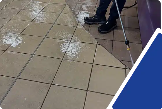 A close-up view of wet, light-colored floor tiles next to a darker carpeted area, framed by a blue graphic.