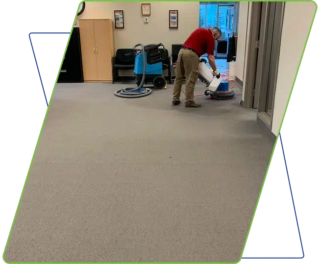 A person vacuuming a carpeted office floor, framed by faint blue and green lines.