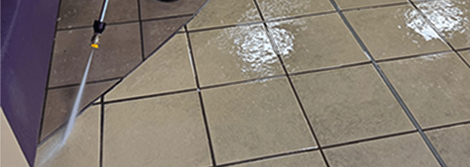 Close-up of wet, light-colored square floor tiles.